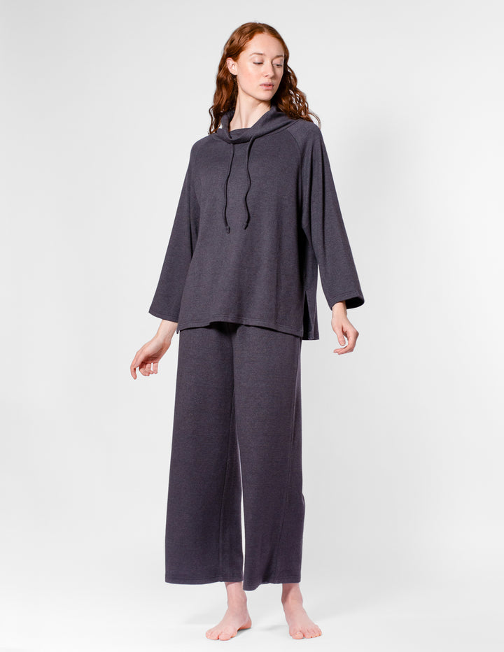 Woman wearing a dark gray long-sleeve top and wide-leg pants on a white background