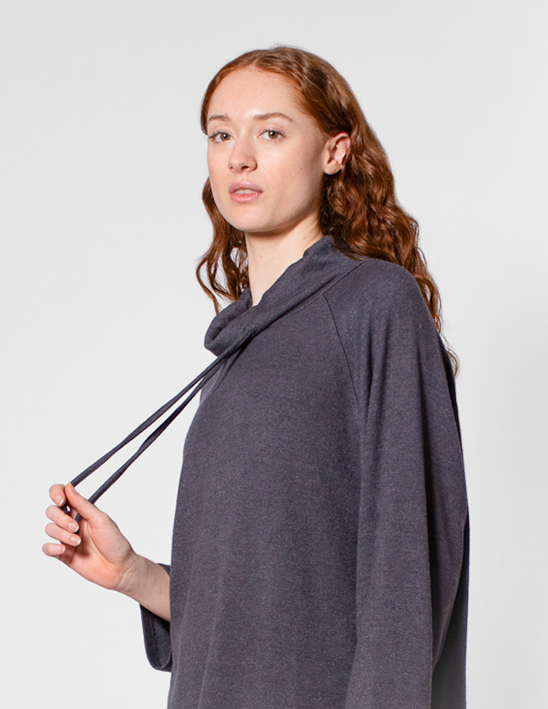 Woman wearing a gray poncho against a plain background