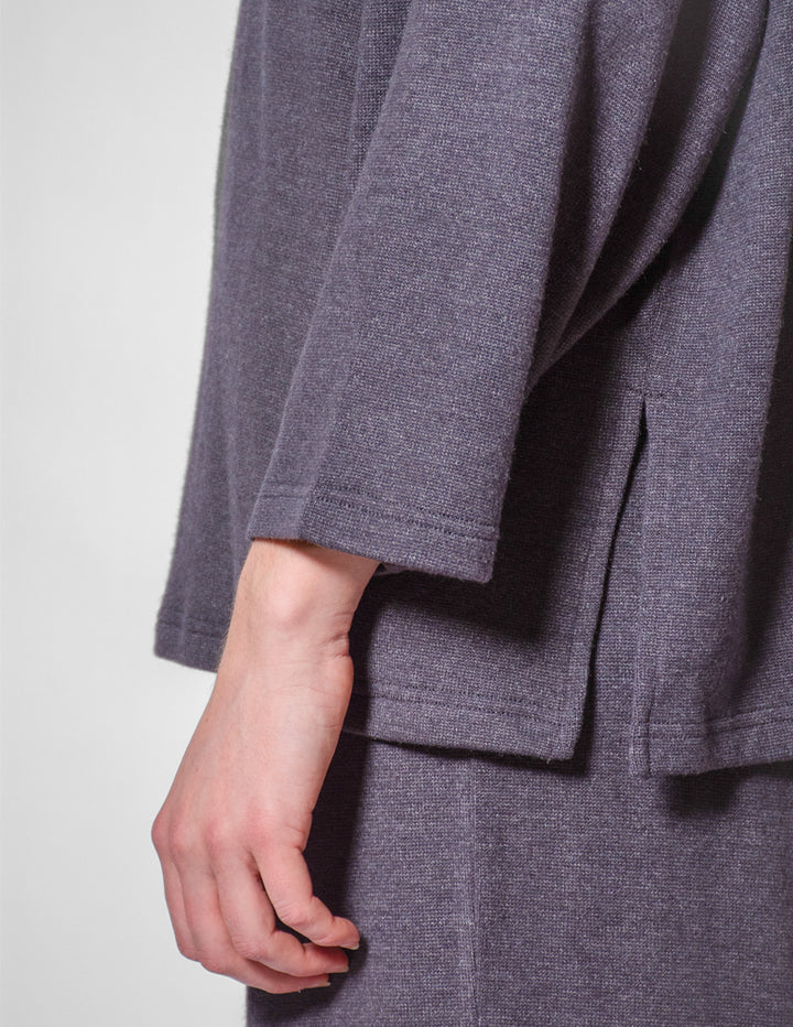 Close-up of a person wearing a gray textured coat with a plain background