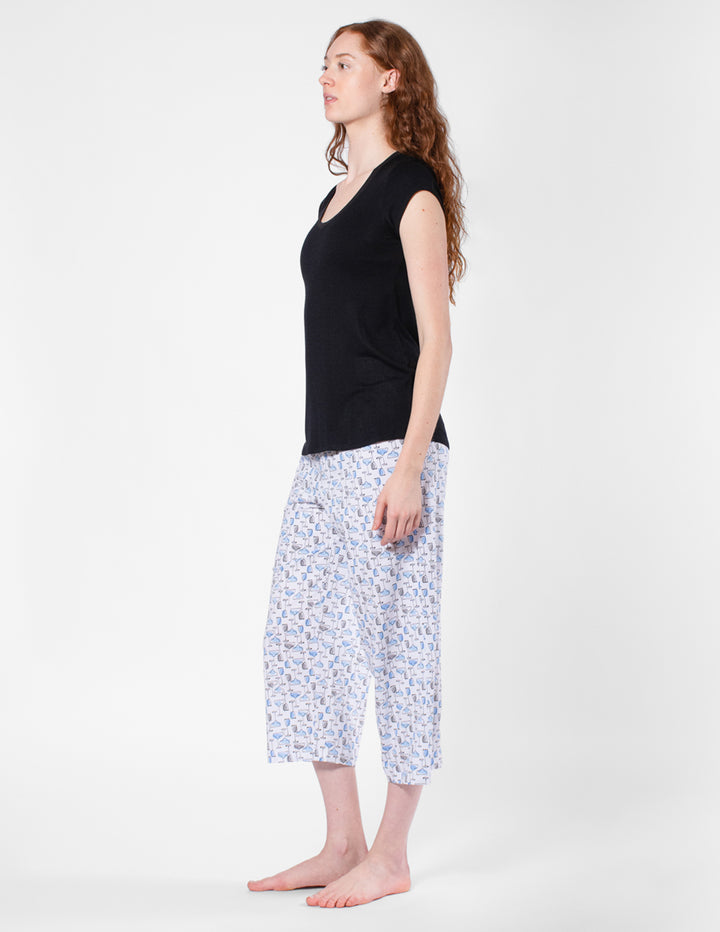 Woman wearing a black top and patterned capri pants on a white background