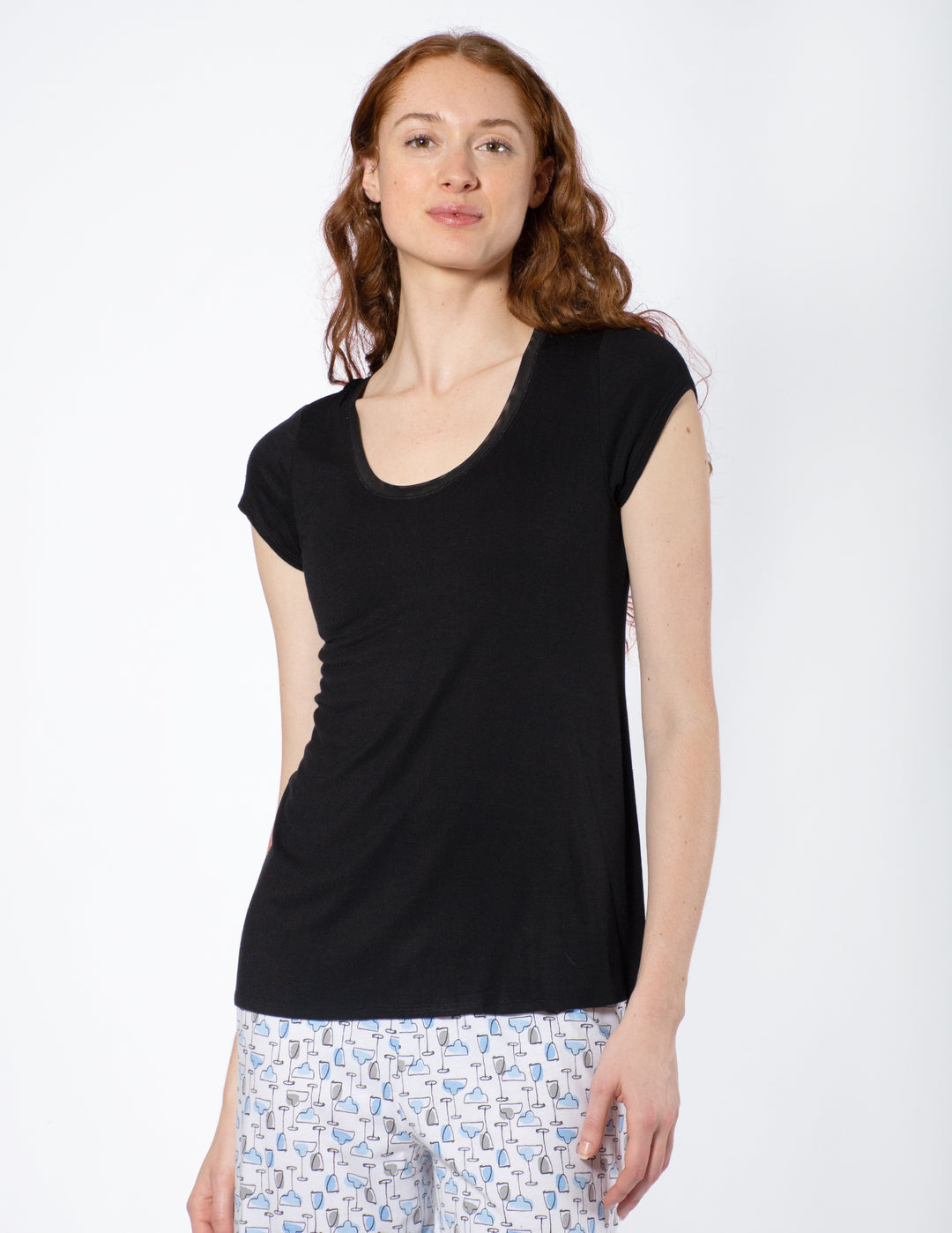 Woman wearing a black sleeveless top and patterned pants on a white background