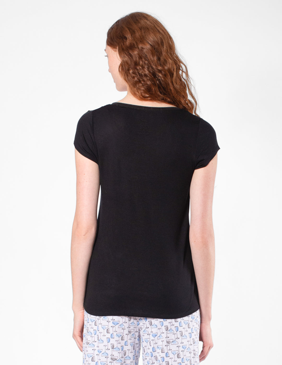 Woman wearing a black t-shirt and patterned pants on a white background