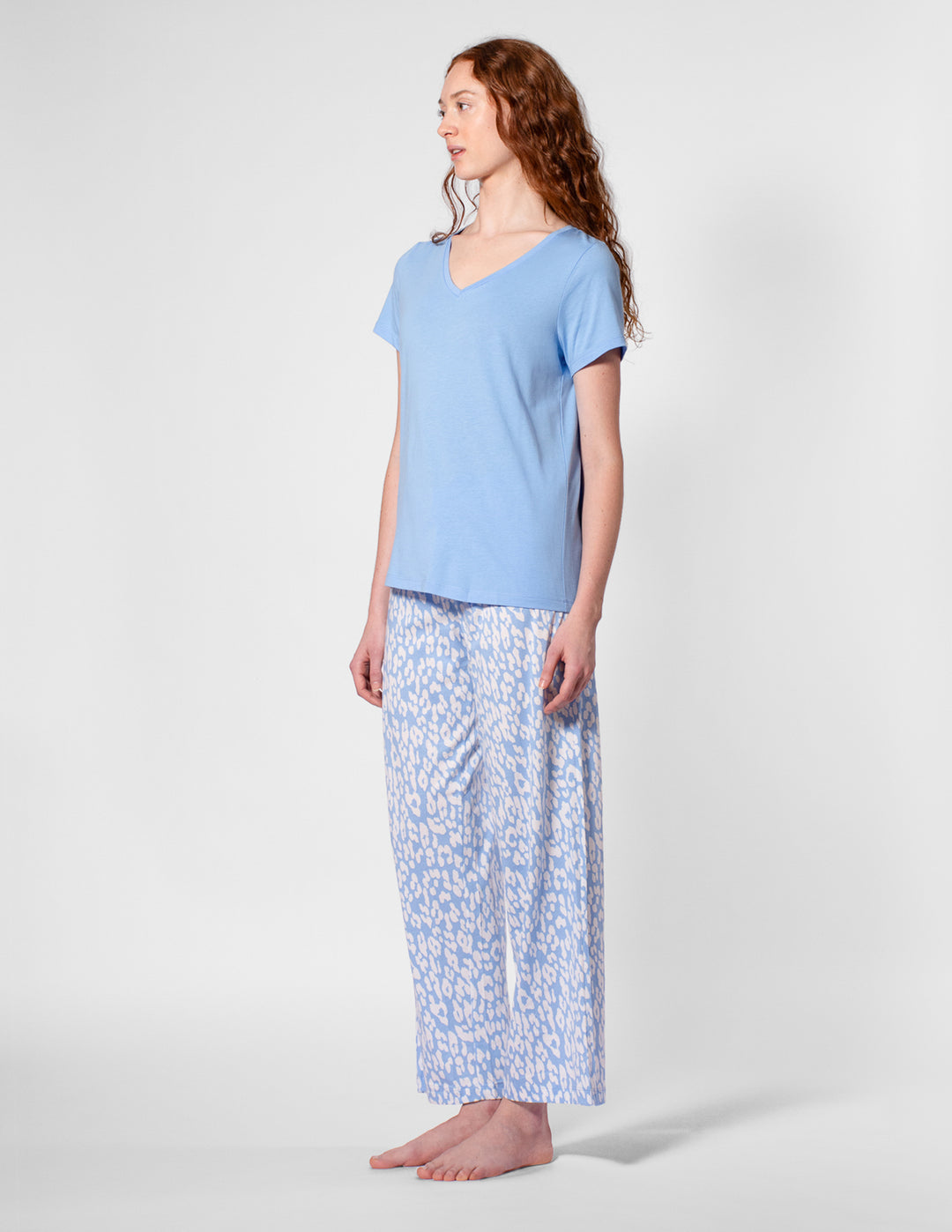 Woman wearing a light blue pajama set with a white background