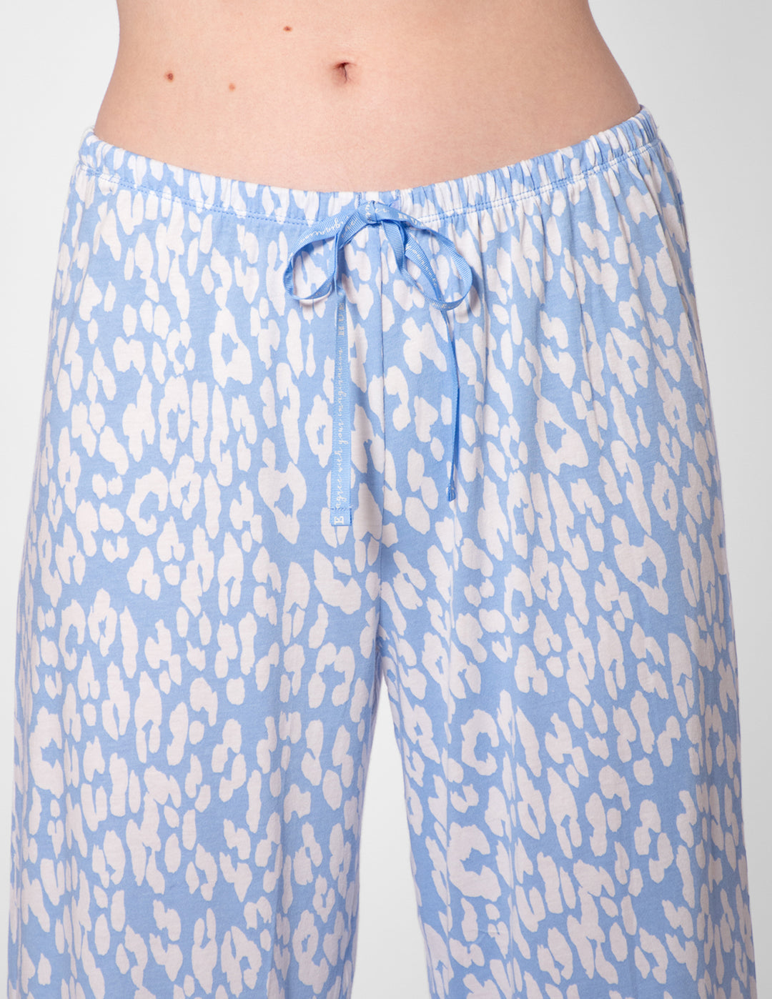 Light blue pajama pants with white animal print pattern on a plain background