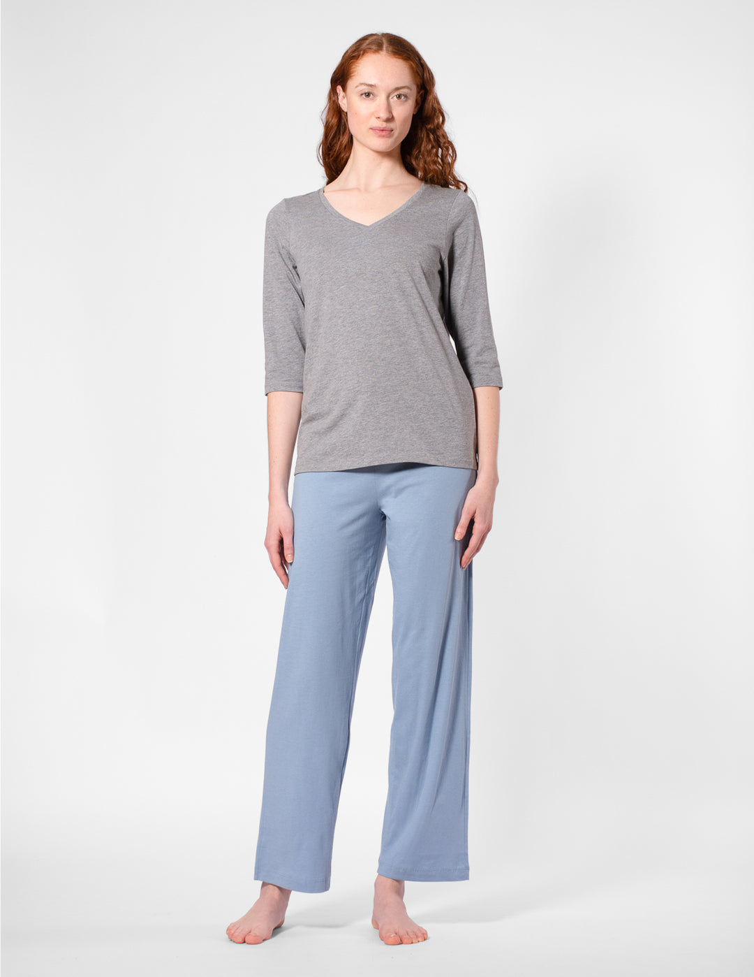 Woman wearing a gray top and light blue pants on a white background