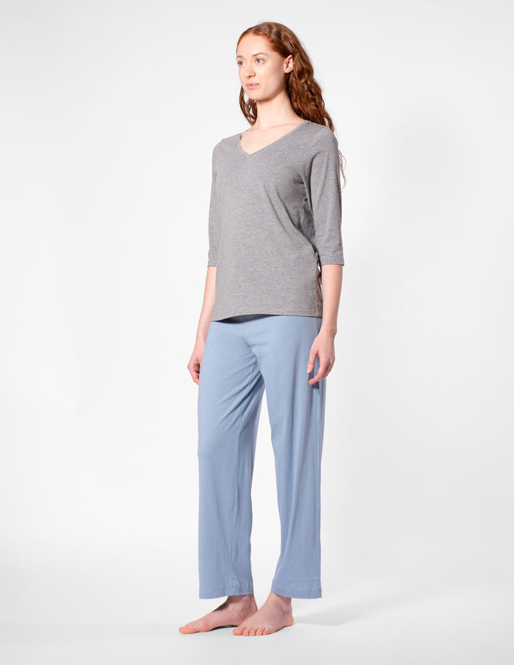 Woman wearing a gray top and light blue pants on a white background
