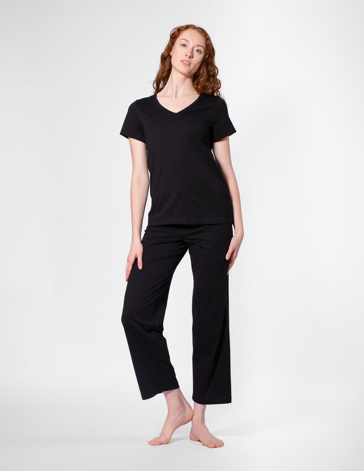 Woman wearing a black t-shirt and black pants on a white background