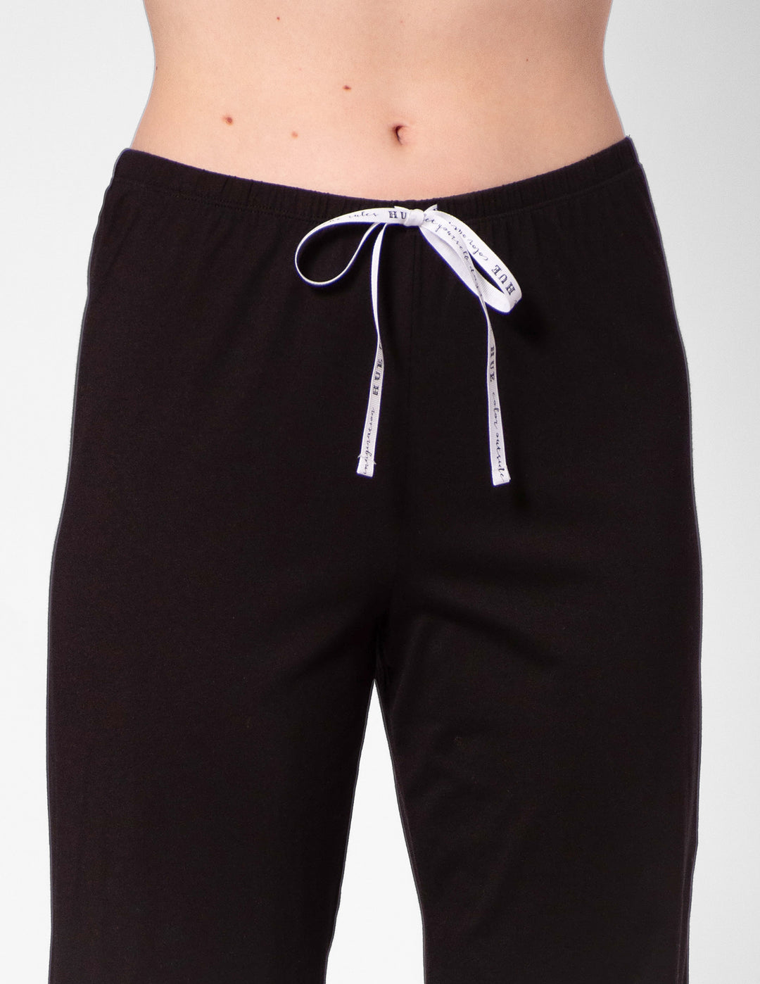 Black pants with a white drawstring on a gray background
