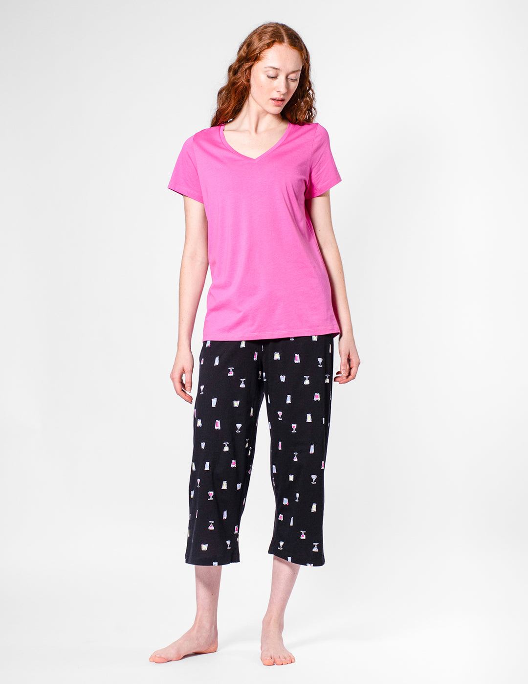 Woman wearing a pink top and black patterned pants on a white background