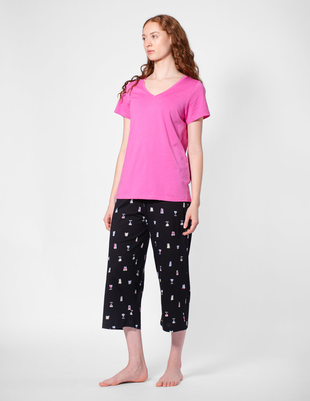 Woman wearing a pink top and black capri pants with a pattern on a white background