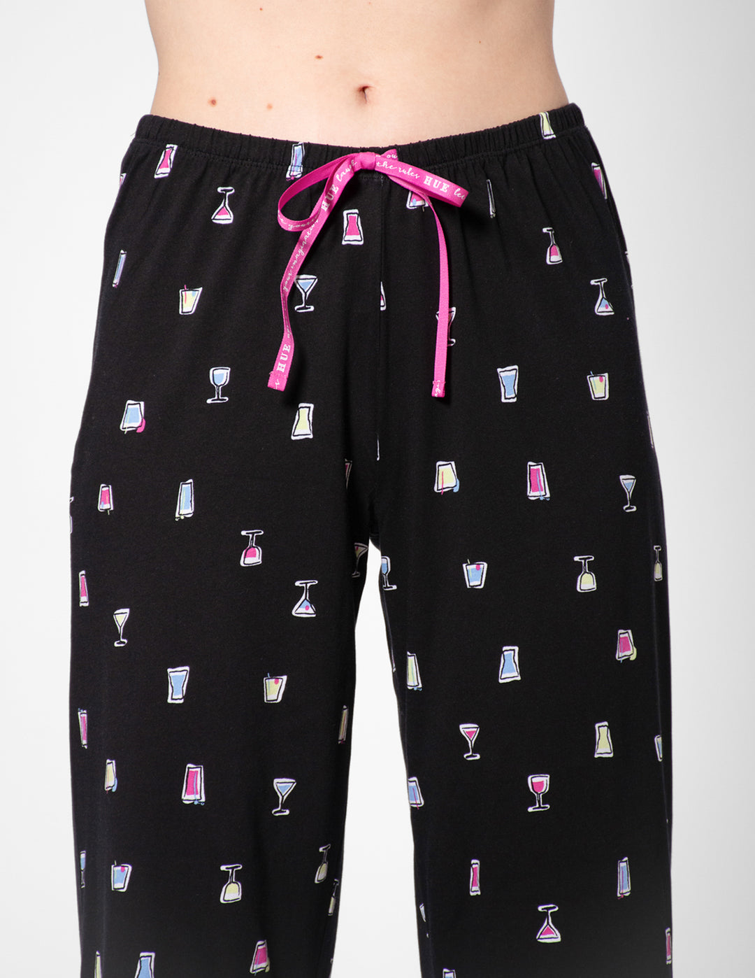 Black pajama pants with cocktail pattern and pink drawstring on a white background