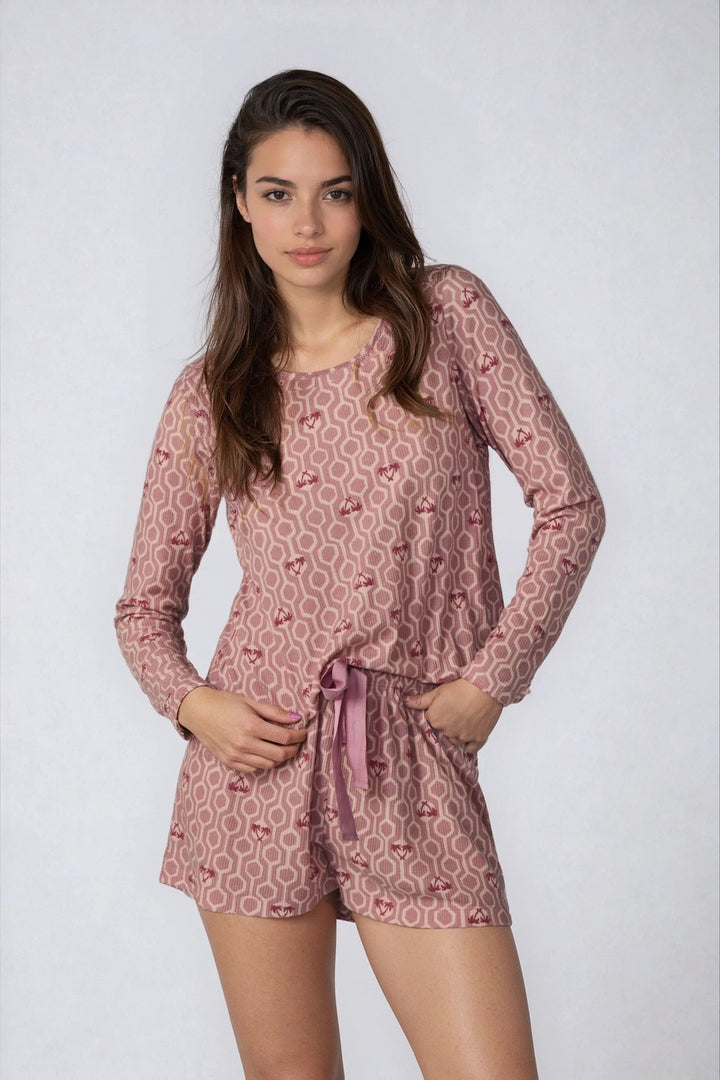 Woman wearing a pink patterned pajama set on a white background