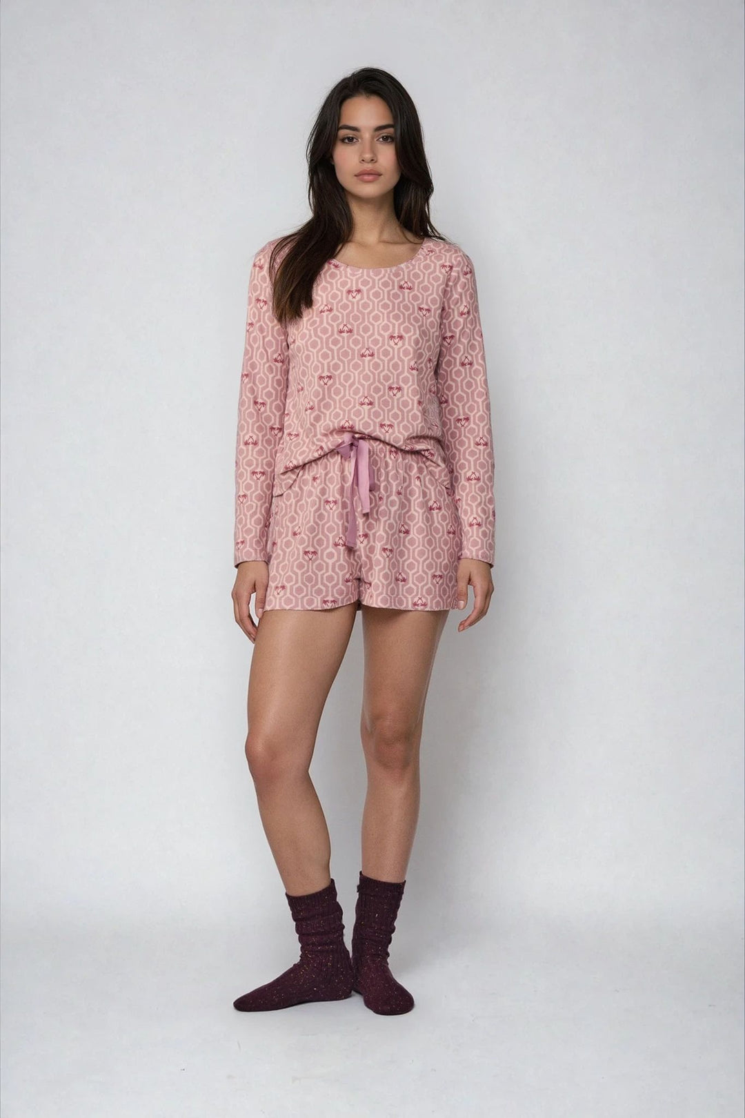 Woman wearing a pink patterned pajama set on a white background