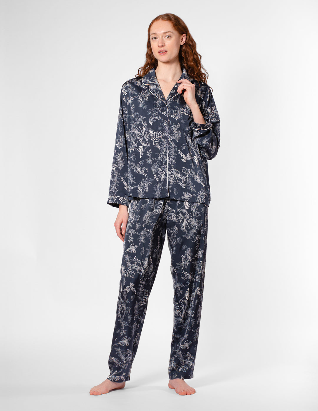 Woman wearing a navy floral pajama set on a white background