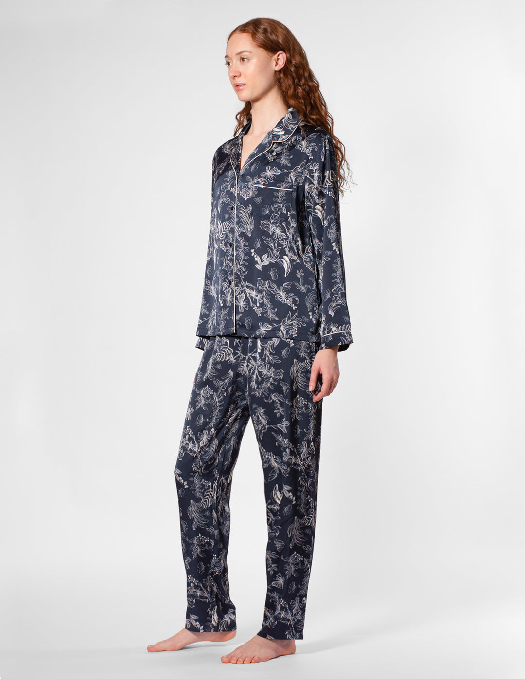 Person wearing a navy floral pajama set on a white background