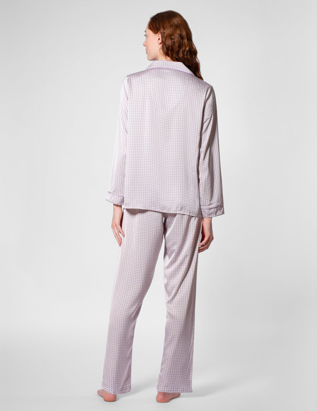 Person wearing a light purple checkered pajama set on a white background