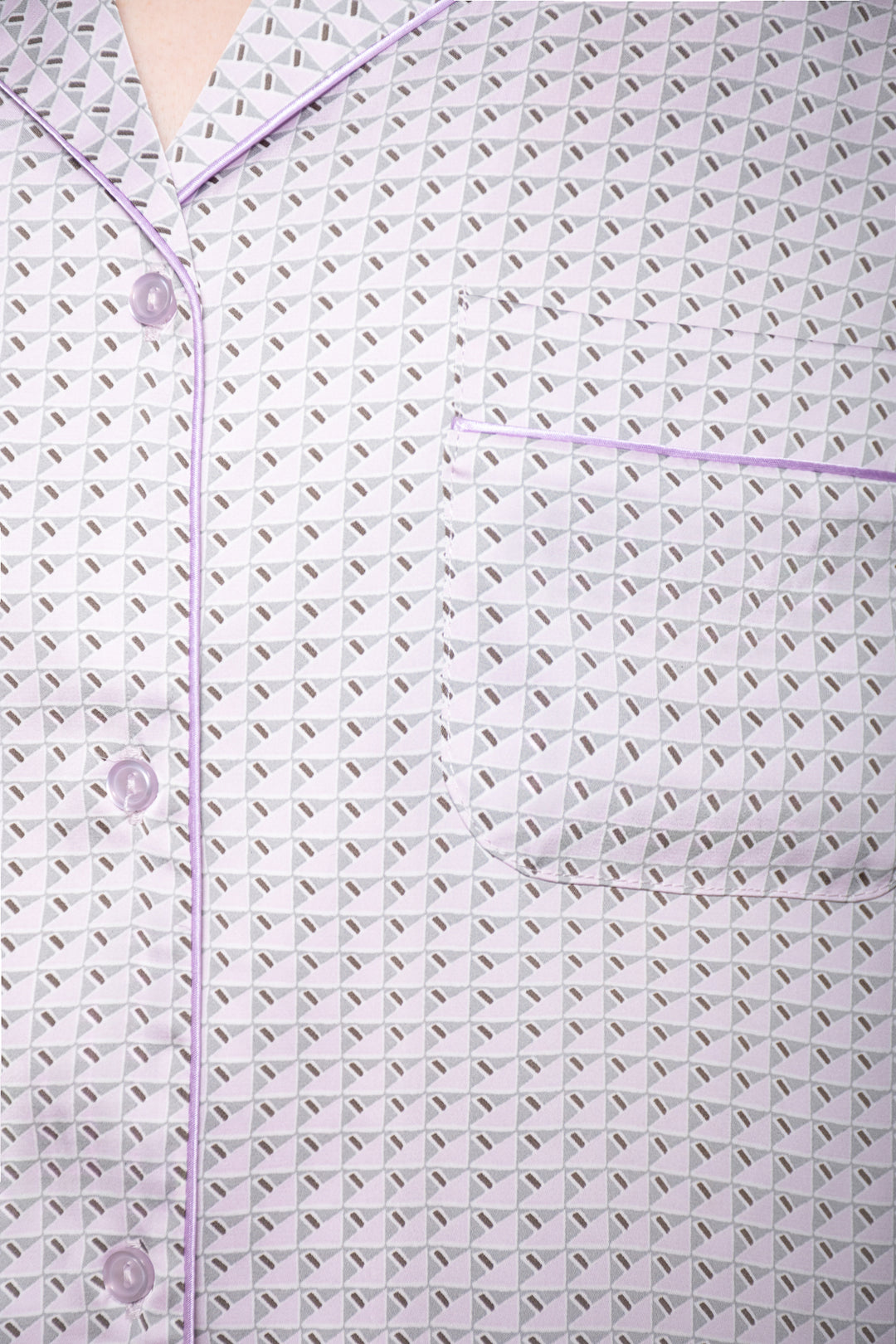 Close-up of a textured fabric with a subtle pattern and buttons on a light purple background
