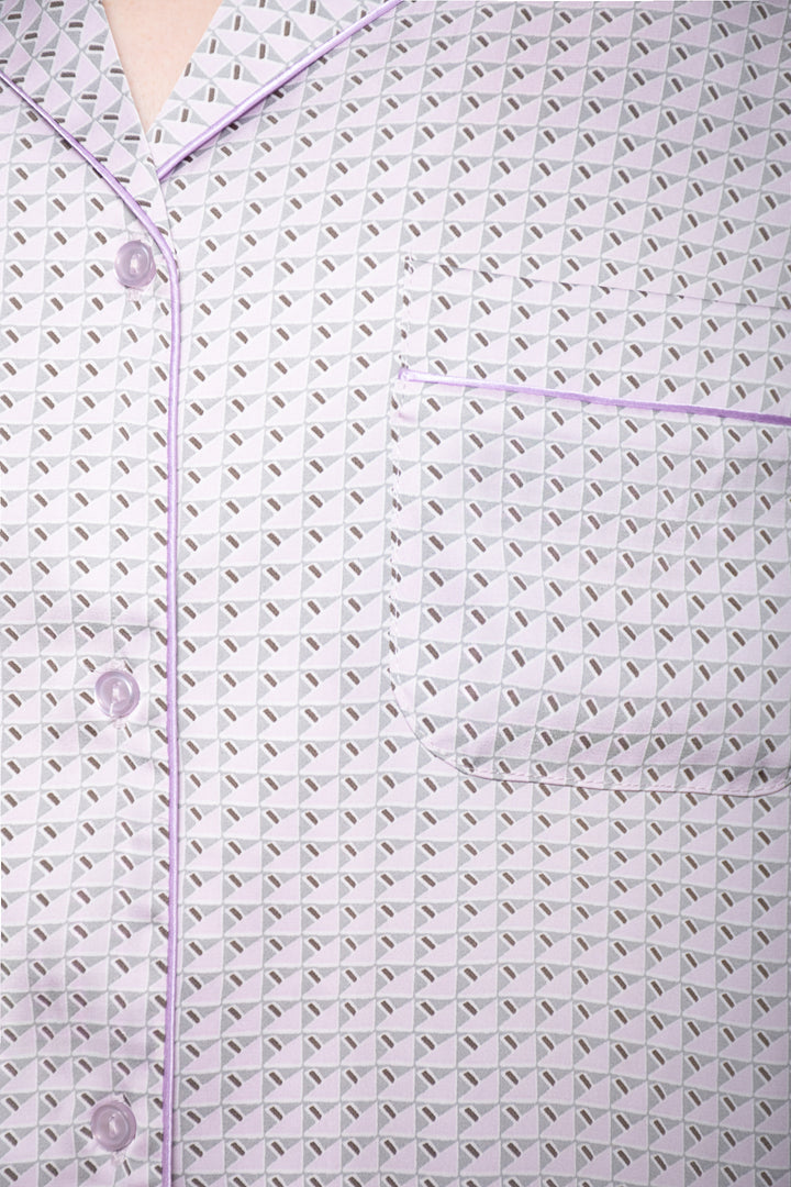 Close-up of a textured fabric with a subtle pattern and buttons on a light purple background