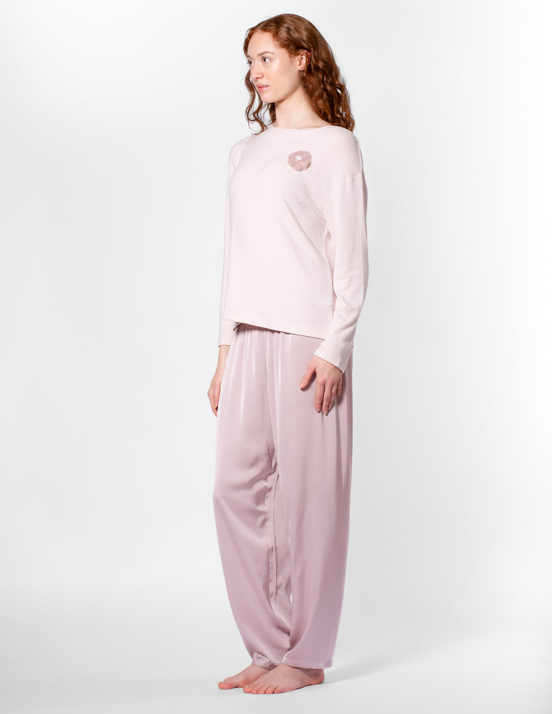 Woman wearing a light pink pajama set on a white background