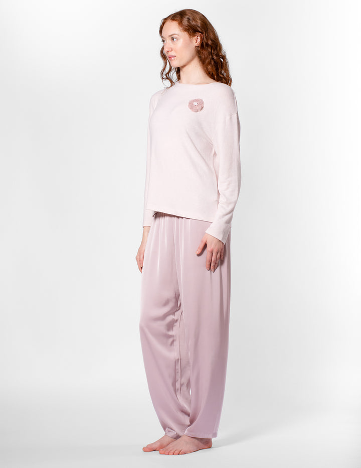 Woman wearing a light pink pajama set on a white background