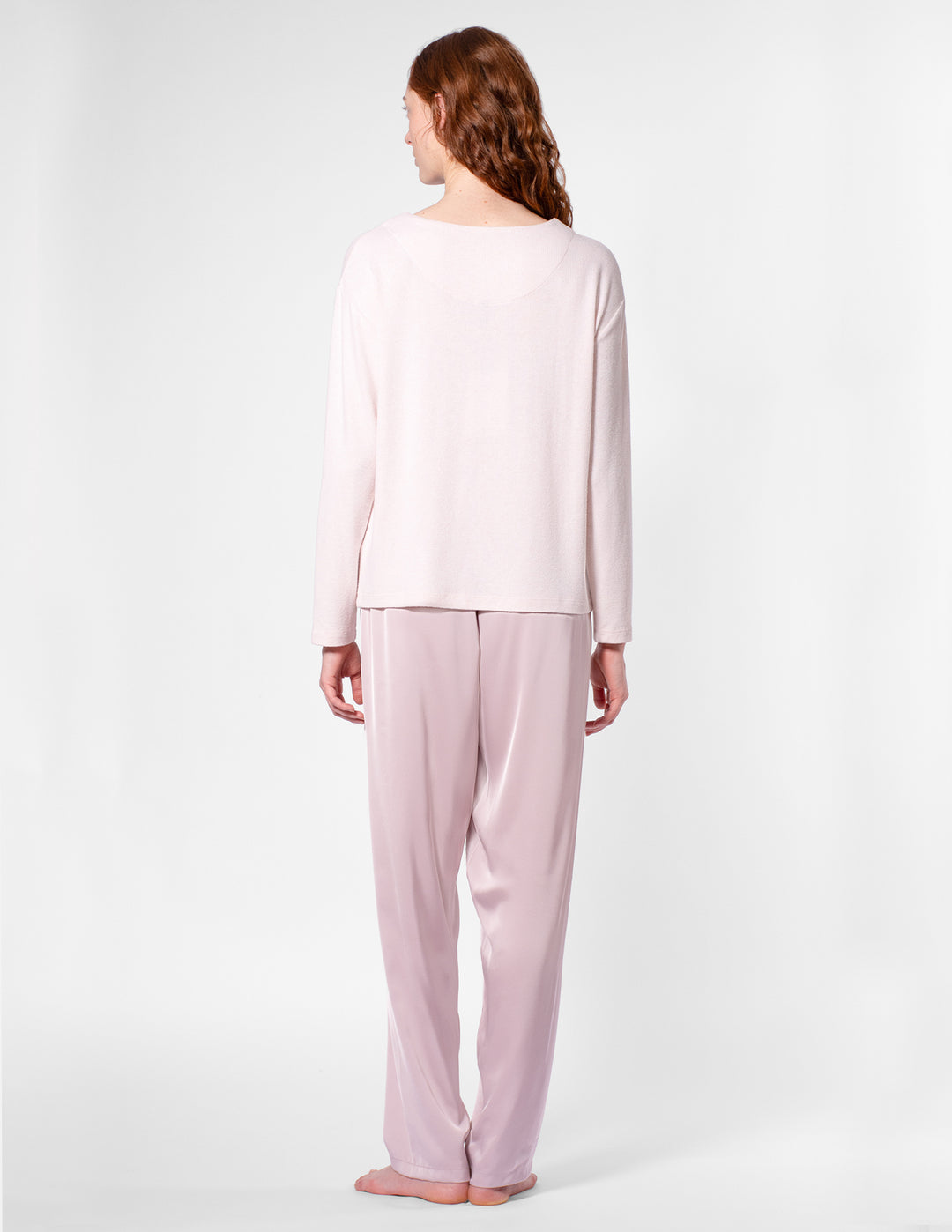 Person wearing light pink pajama set on a white background