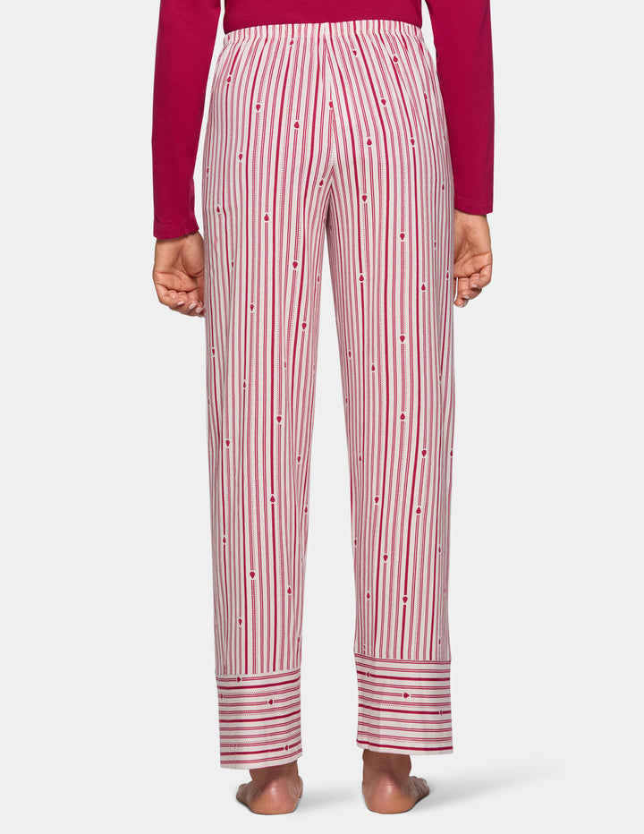 Back view of a model wearing long stripe pajama pants and a long sleeve pink pj top.