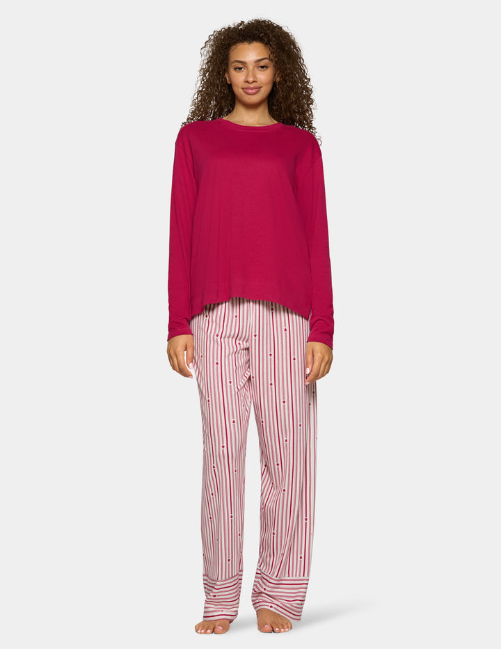 A model wearing long stripe pajama pants and a long sleeve pink pj top.