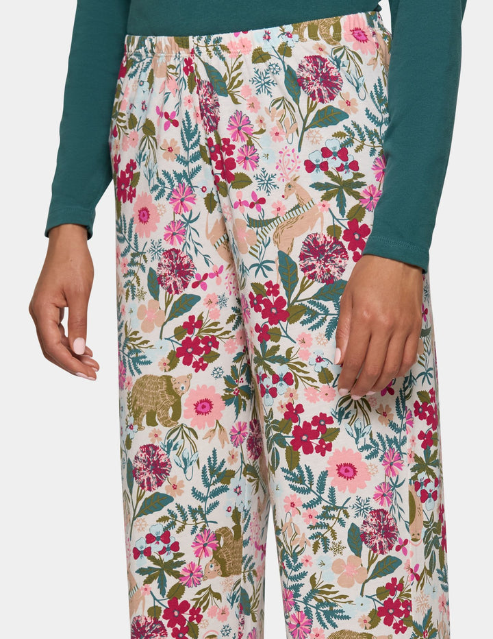 A model wearing long floral print pajama pants and a long sleeve green pajama top.