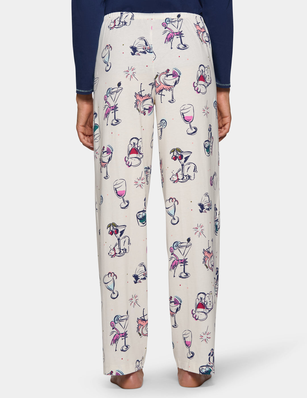 A backside view of a model wearing off-white pajama pants featuring an animal print design, pair with a long sleeve blue top.