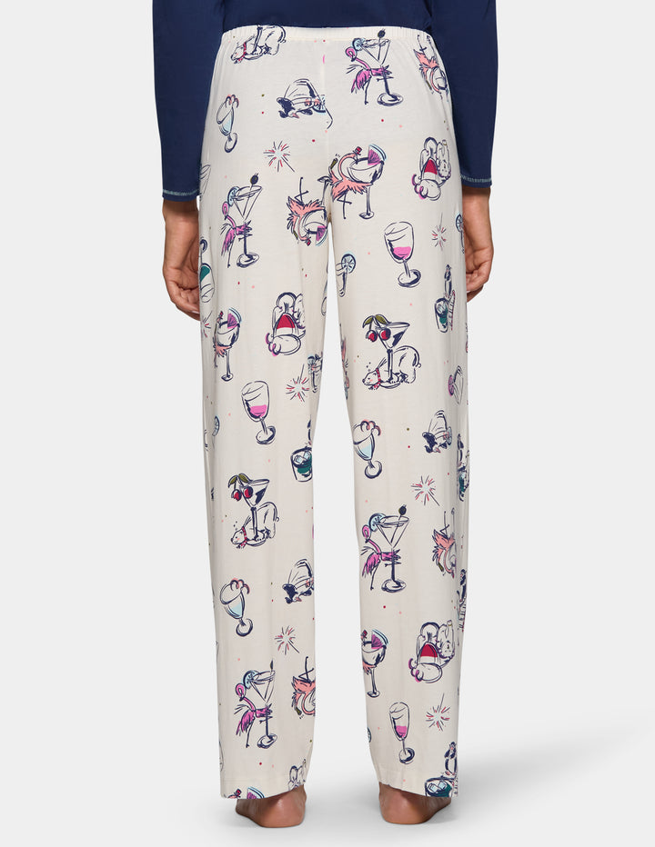 A backside view of a model wearing off-white pajama pants featuring an animal print design, pair with a long sleeve blue top.
