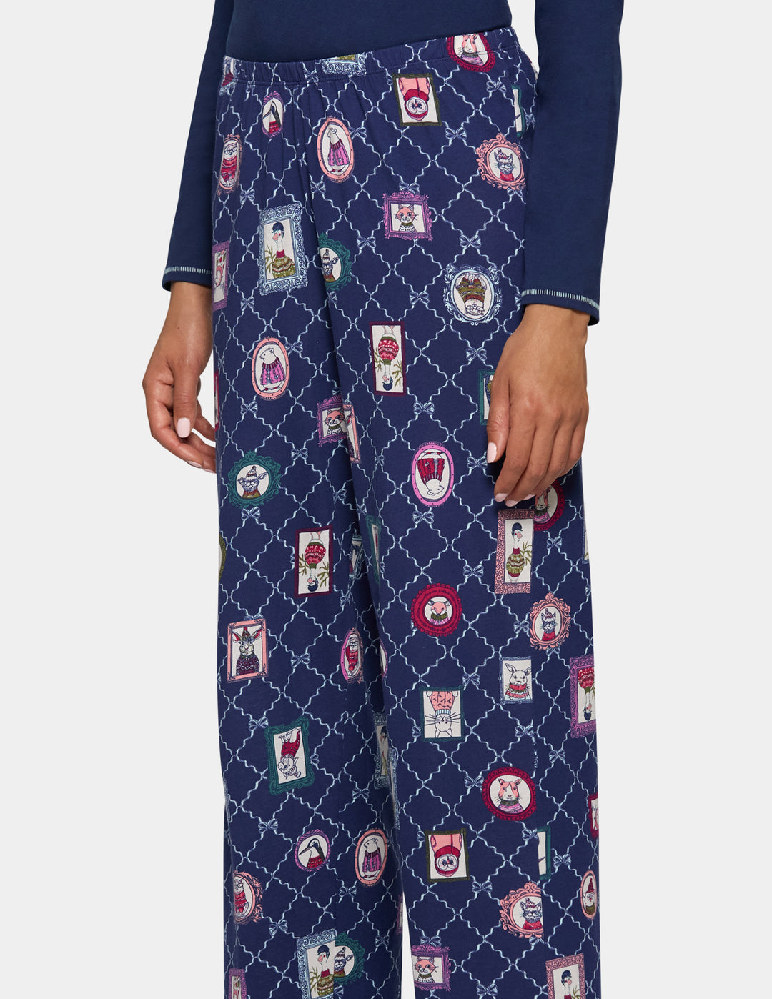 A person wearing navy blue wide-leg trousers with an allover embroidered patchwork and trellis pattern, paired with a navy long-sleeve top, shown against a light gray studio background.