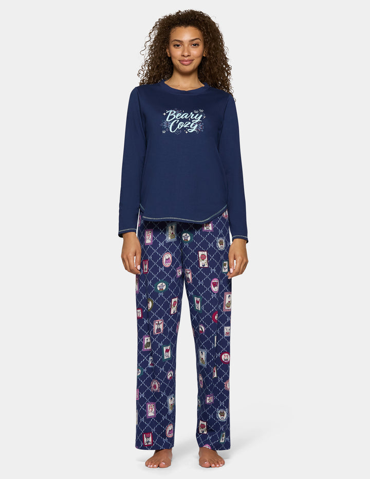 A model wearing navy blue pajama pants with an animal pattern and a long sleeve navy shirt.
