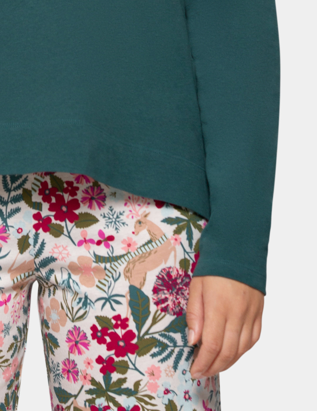 Close-up of a person wearing a dark teal long-sleeve top and floral print leggings with a deer pattern, against a light gray background.
