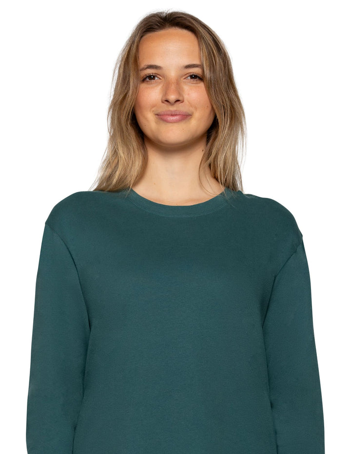 A woman with blonde hair wearing a dark teal green long-sleeve crewneck sweatshirt, shown from the chest up against a plain white background.