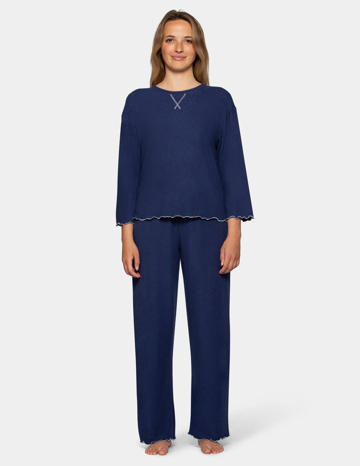 A model wearing navy pajama pants and a long sleeve matching shirt.