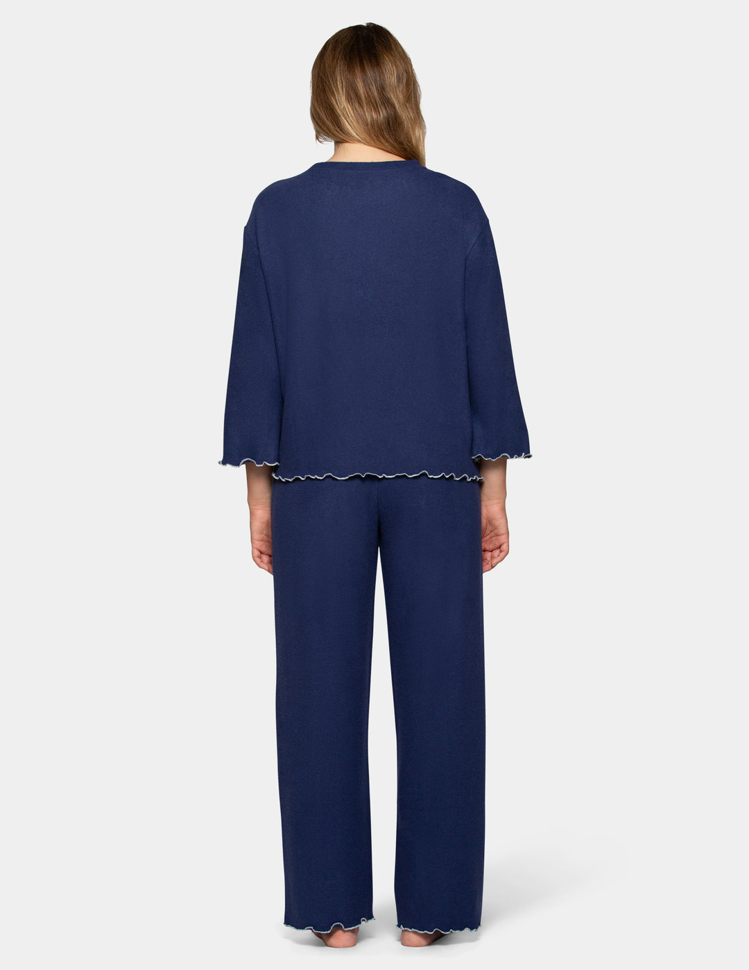 A back view of a model wearing navy pajama pants and a long sleeve matching shirt.