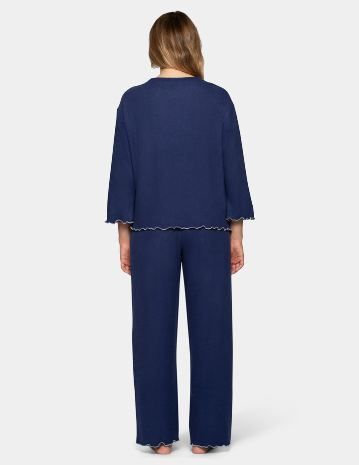 A back view of a model wearing navy pajama pants and a long sleeve matching shirt.