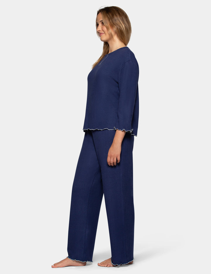 A model wearing navy pajama pants and a long sleeve matching shirt.