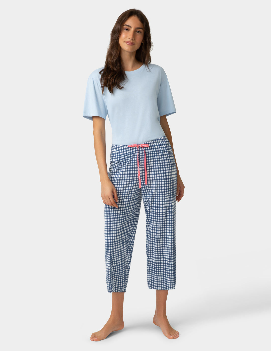 Woman wearing gingham PJ capri in blue and white check pattern and pajama top