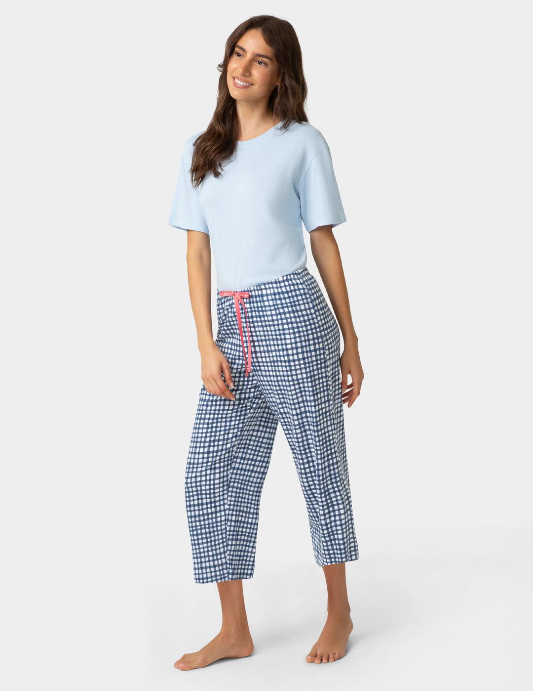 Woman wearing gingham PJ capri in blue and white check pattern and pajama top