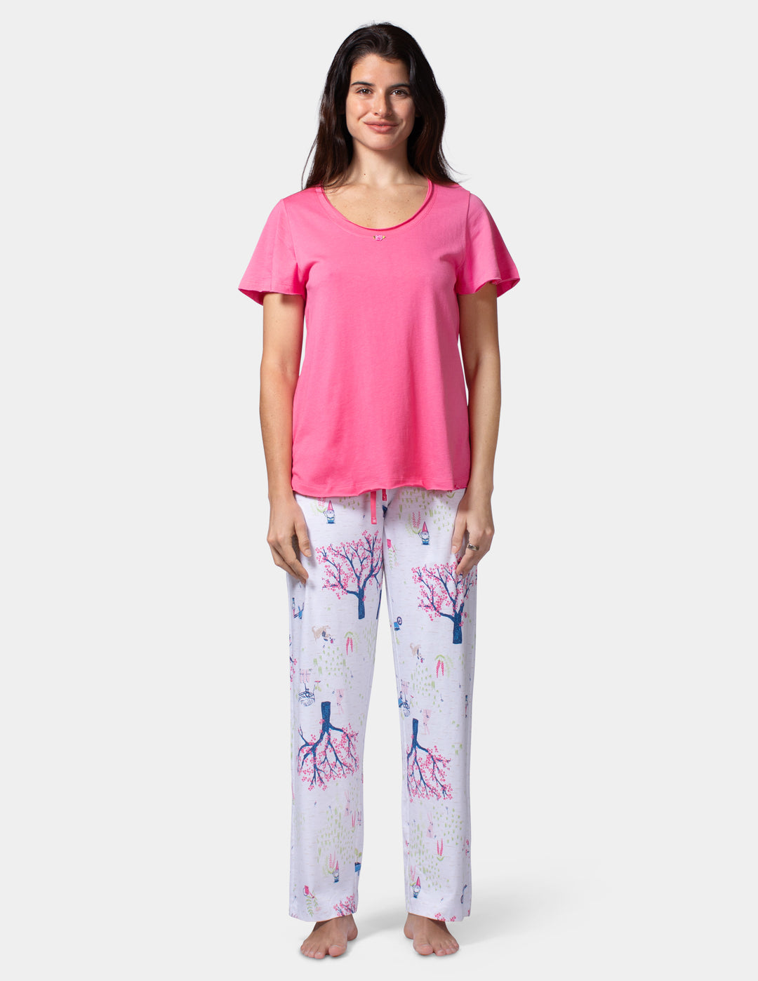 Woman wearing a pink top and patterned pants on a white background