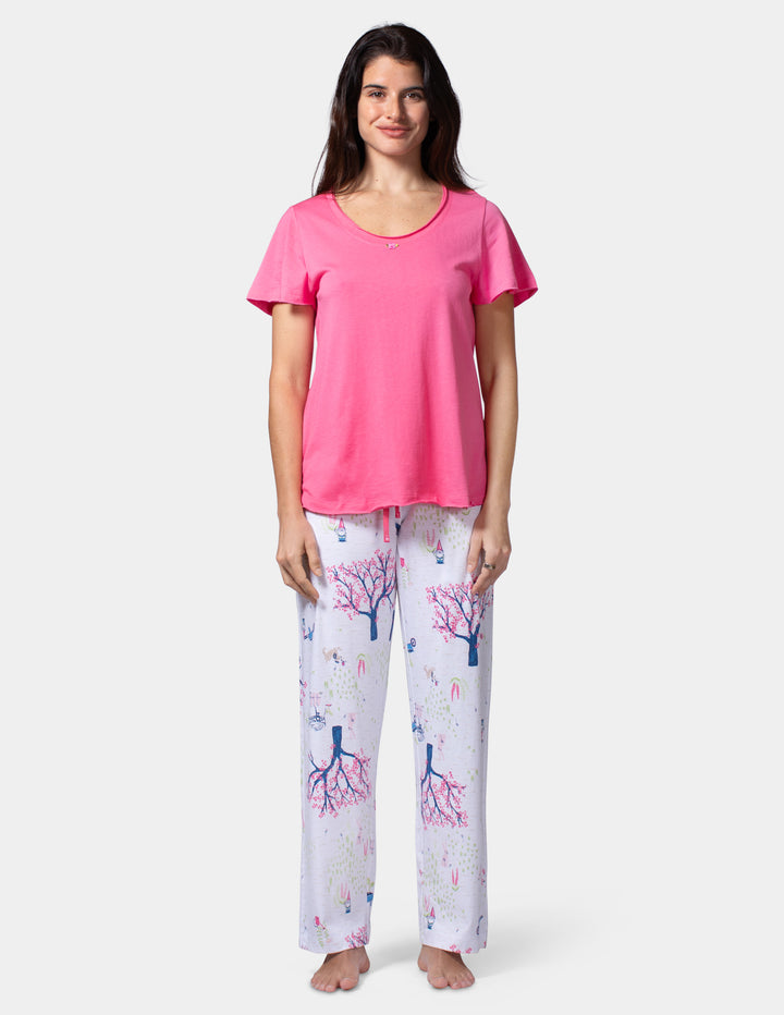 Woman wearing a pink top and patterned pants on a white background