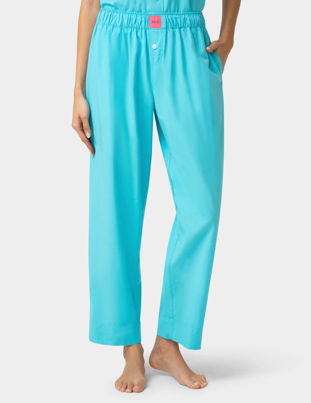 Turquoise pajama pants worn by a person on a light gray background