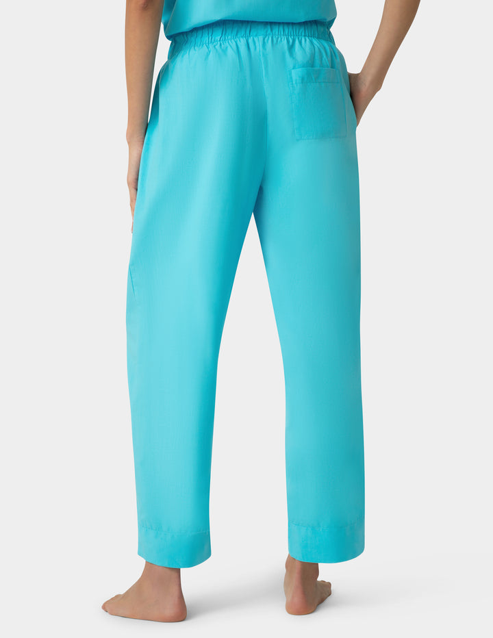 Turquoise pants worn by a person on a white background
