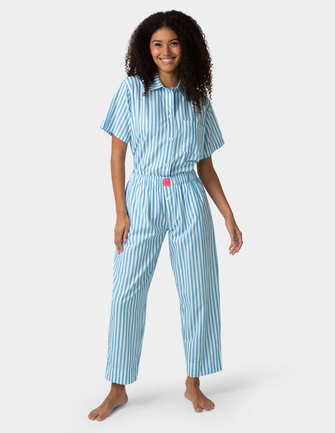 Woman wearing a blue and white striped pajama set on a white background