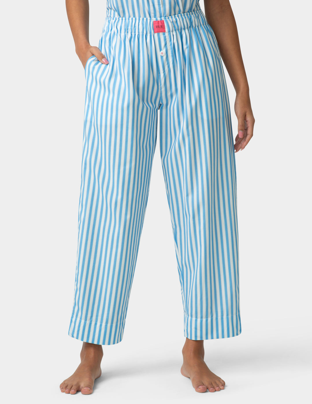 Person wearing blue and white striped pajama pants on a white background