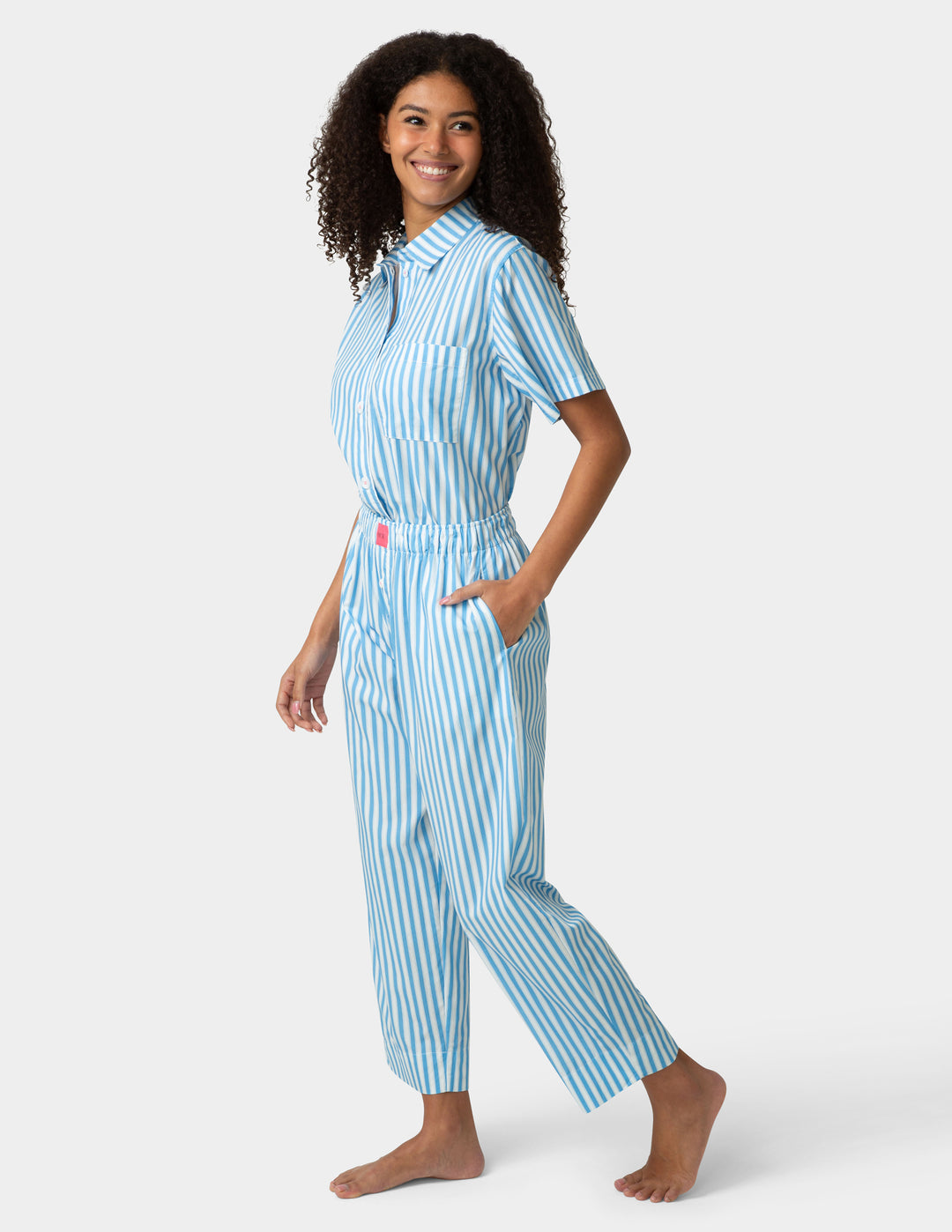 Woman wearing a blue and white striped pajama set on a white background