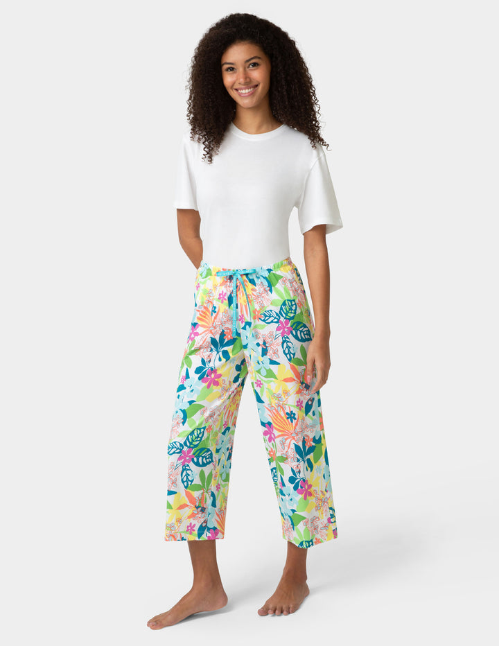 Woman wearing a white t-shirt and colorful floral pj pants on a white background