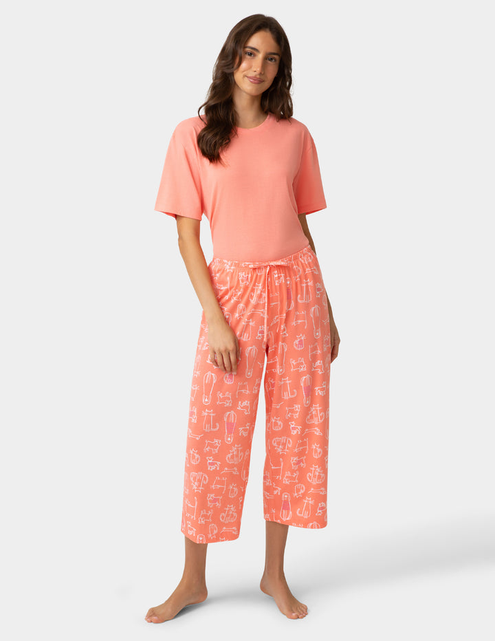 Woman wearing a coral pajama set with a white background