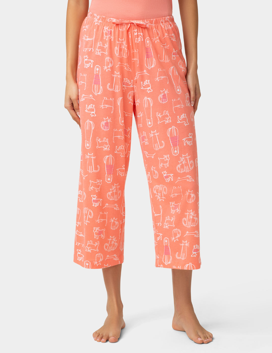 Person wearing coral capri pants with a pattern on a white background
